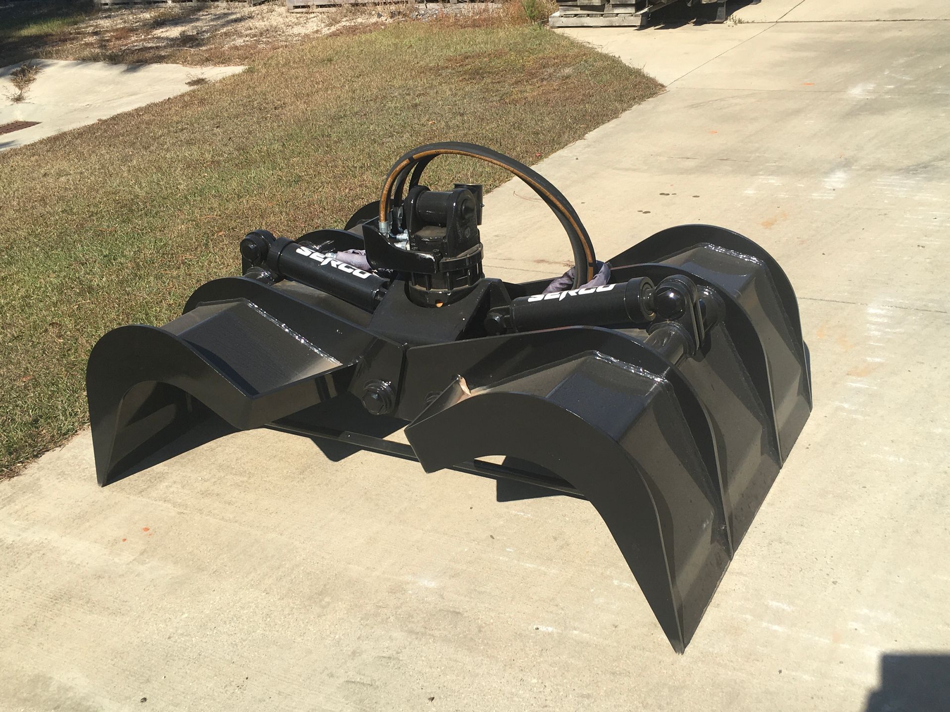 A black bucket with a hose attached to it is sitting on a sidewalk.