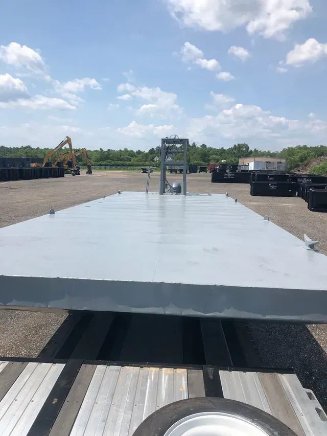 A flatbed trailer is parked in a parking lot on a sunny day.