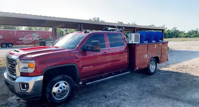 A red truck with a utility bed is parked in a parking lot.