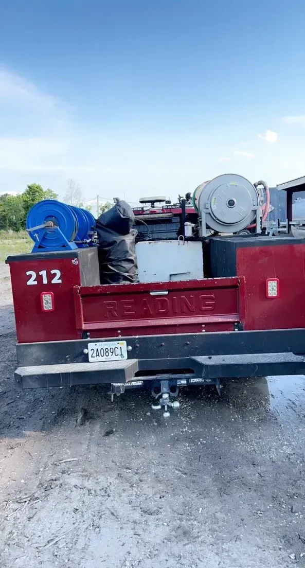 The back of a red truck with a tractor attached to it.