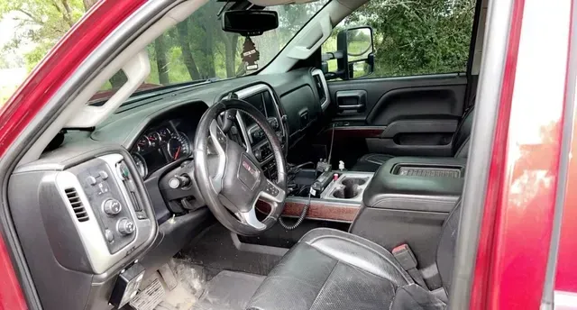 The inside of a red truck with the door open and a steering wheel.