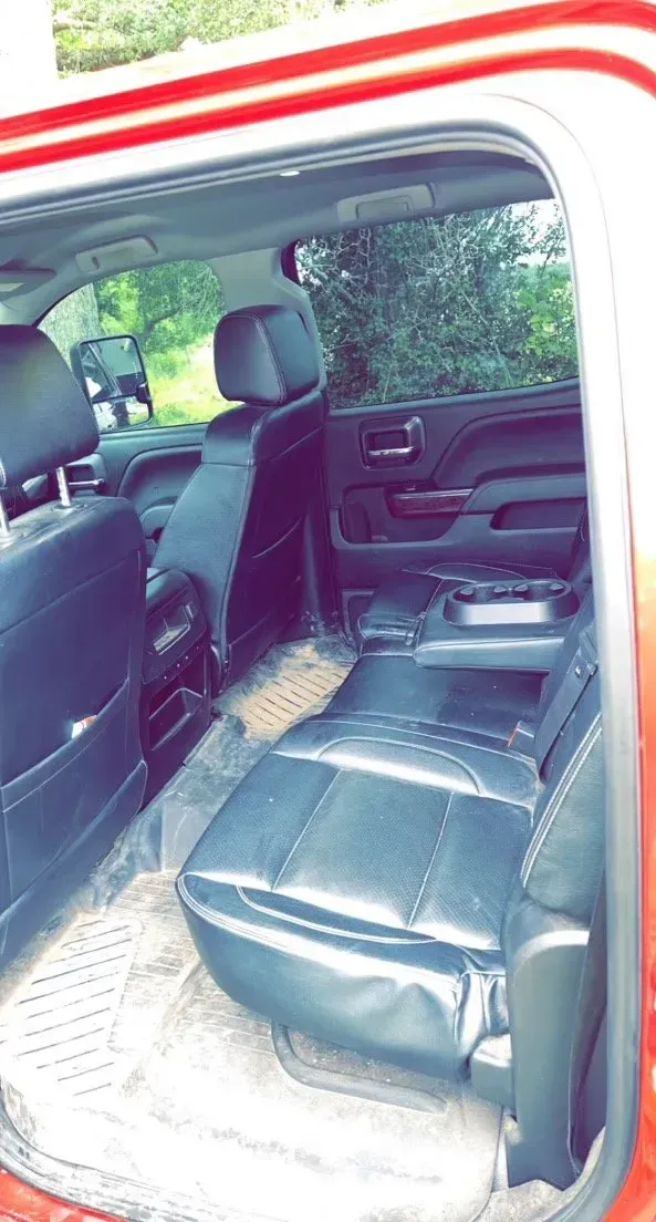The back seat of a red truck with black leather seats.