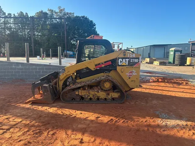 A yellow and black cat skid steer is parked on a dirt road.