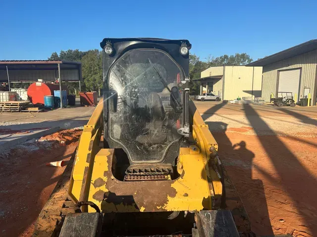 A yellow bulldozer is parked in a dirt lot in front of a building.