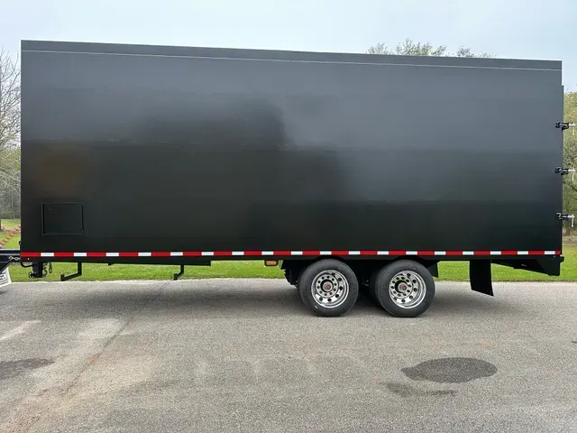 A black trailer is parked on the side of the road.