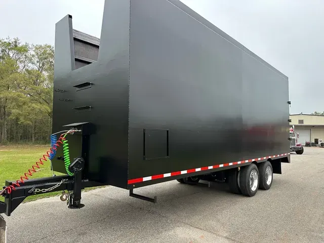 A black trailer is parked on the side of the road.