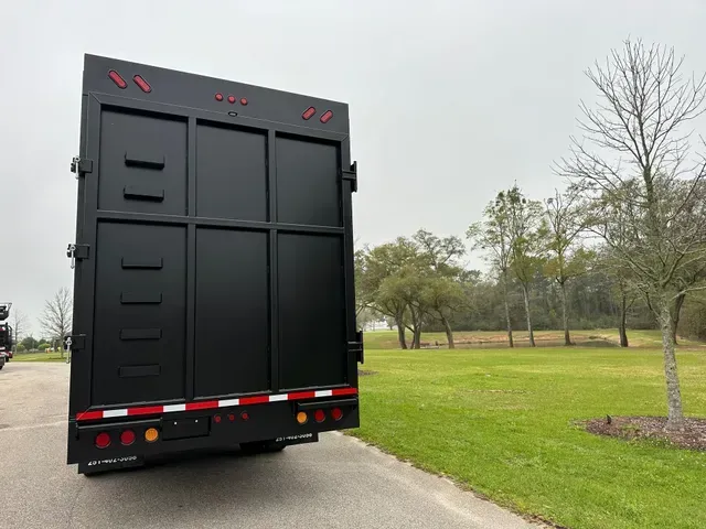 A black truck is parked on the side of a road next to a grassy field.