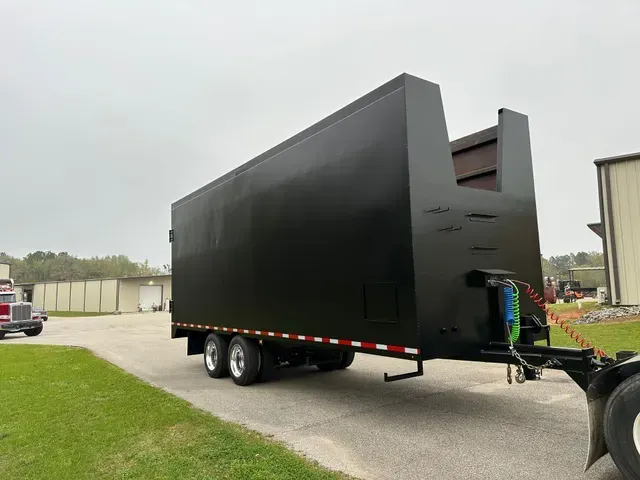 A large black trailer is parked on the side of the road
