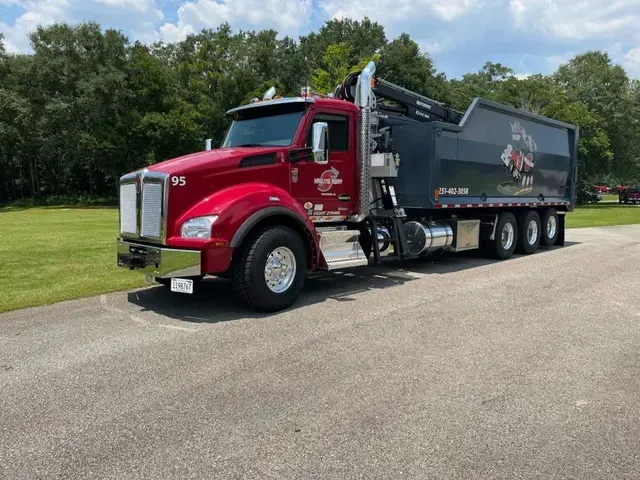 A red dump truck is parked on the side of the road.