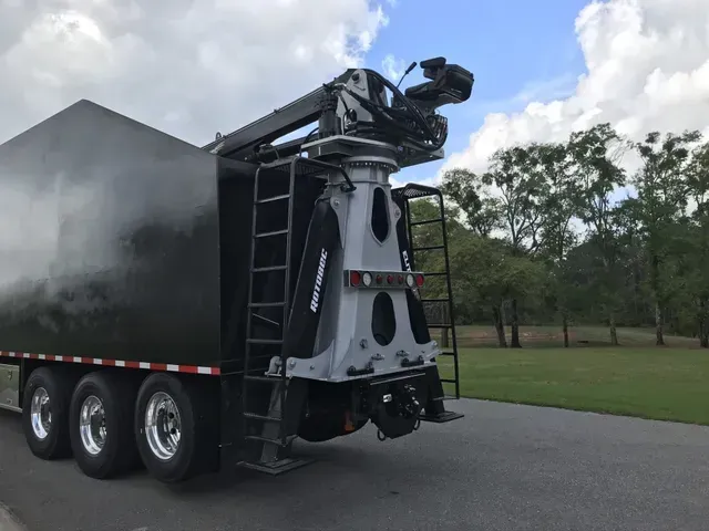 A black truck with a crane on the back is parked on the side of the road