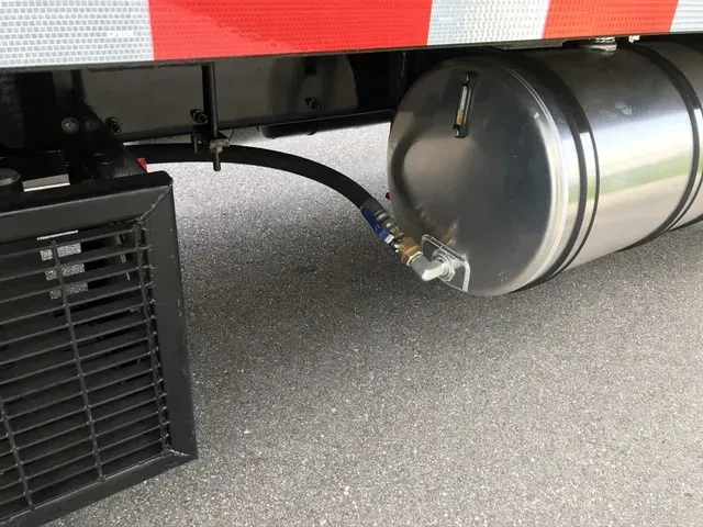 A stainless steel tank is attached to the side of a truck.