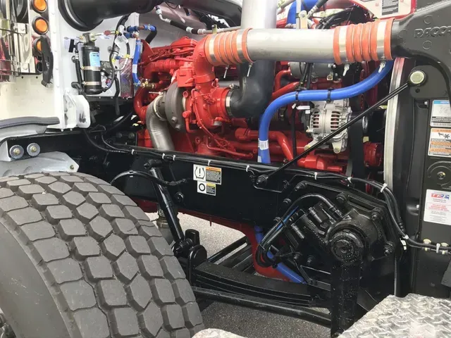 A close up of a truck engine with a tire in the foreground