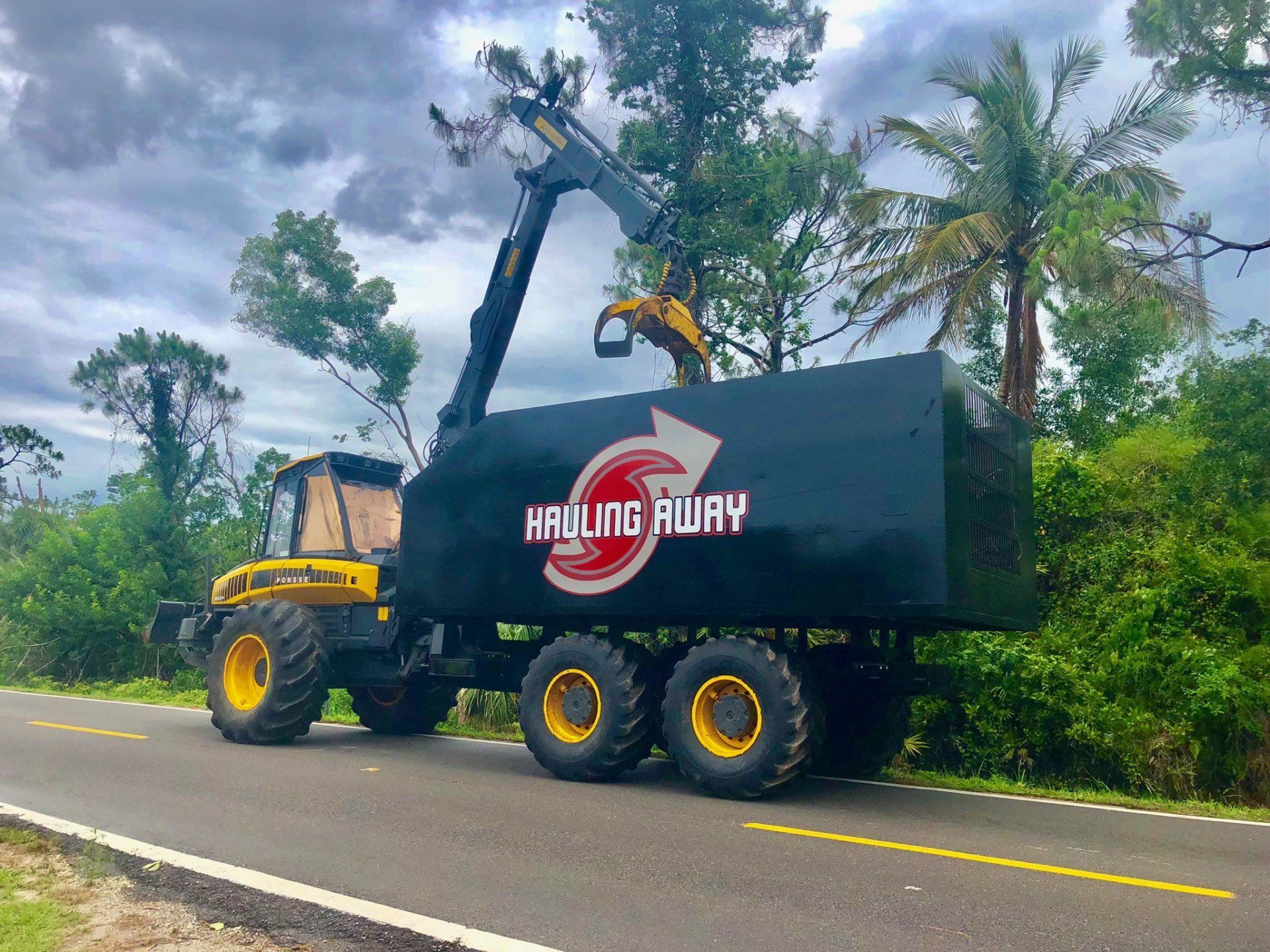 A hauling away truck is parked on the side of the road
