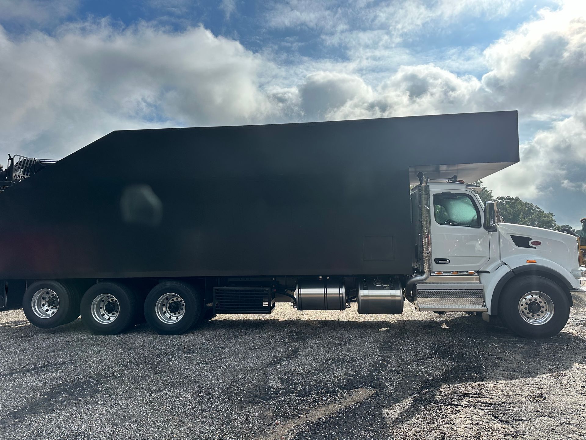 A white dump truck is parked in a gravel lot.