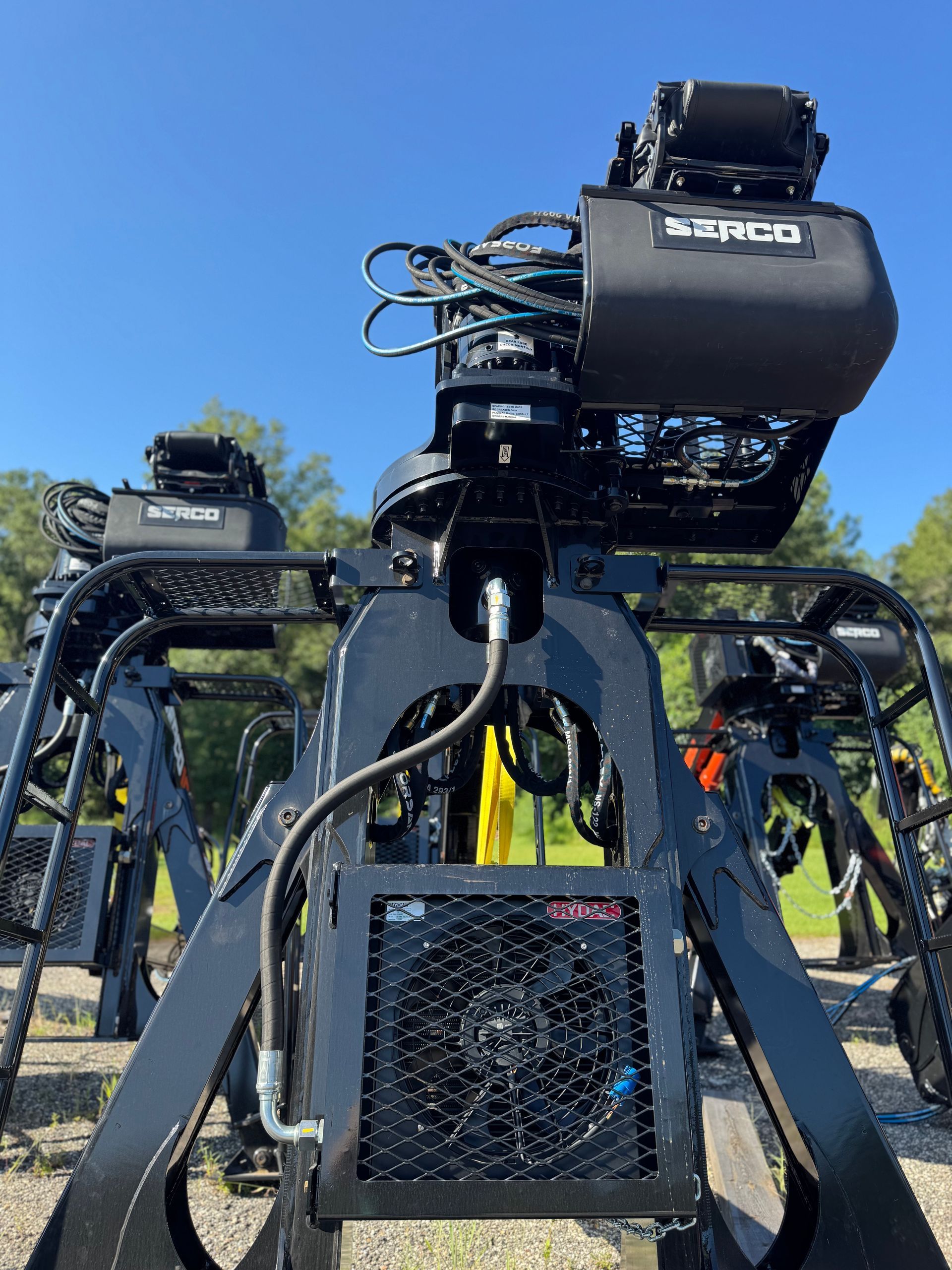 Black robotic arm with electronic components, outdoors.