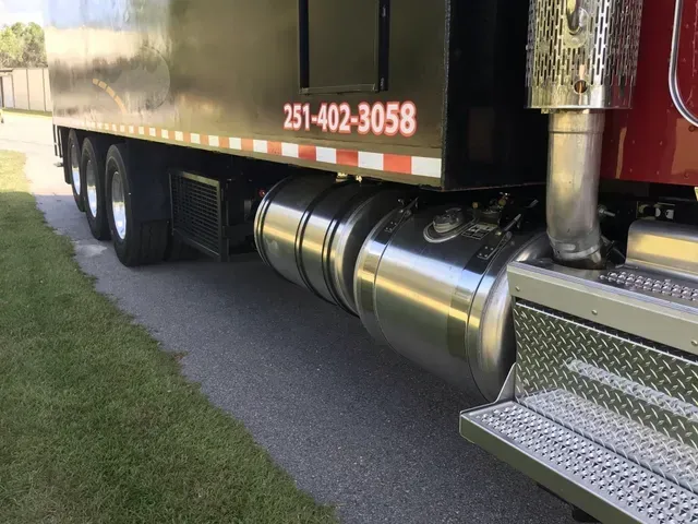 A semi truck with a phone number on the side is parked on the side of the road.