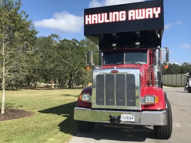 A red hauling away truck is parked on the side of the road
