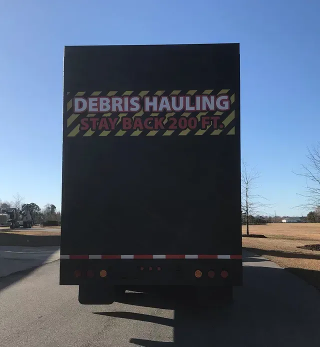 A debris hauling truck is parked on the side of the road