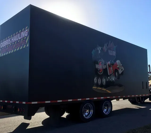 A black truck with the word hauling away on the side