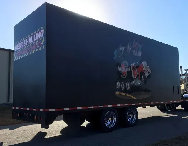 A black trailer is parked on the side of the road.