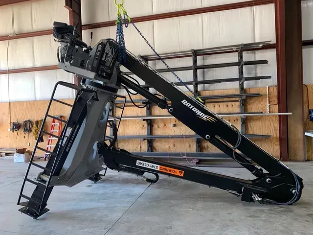 A crane is sitting on the ground in a warehouse.