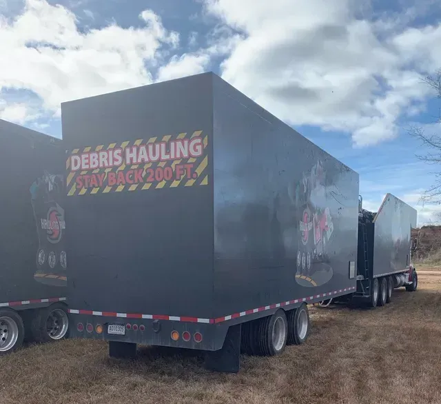 A truck with a trailer attached to it is parked in a field.