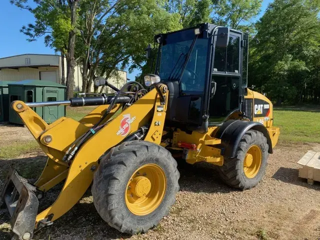 A yellow cat wheel loader is parked in a gravel lot.