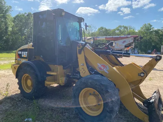 A yellow cat wheel loader is parked in a grassy field.