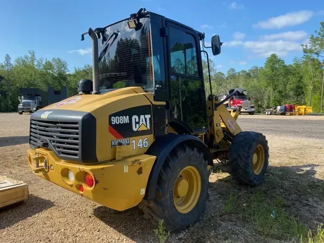 A yellow cat wheel loader is parked in a gravel lot