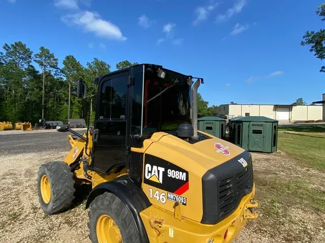 A yellow cat 903m wheel loader is parked in the dirt