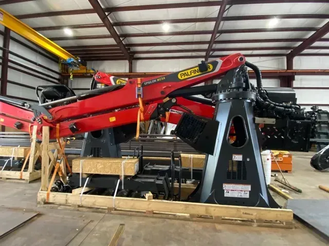 A large crane is sitting in a wooden crate in a warehouse.