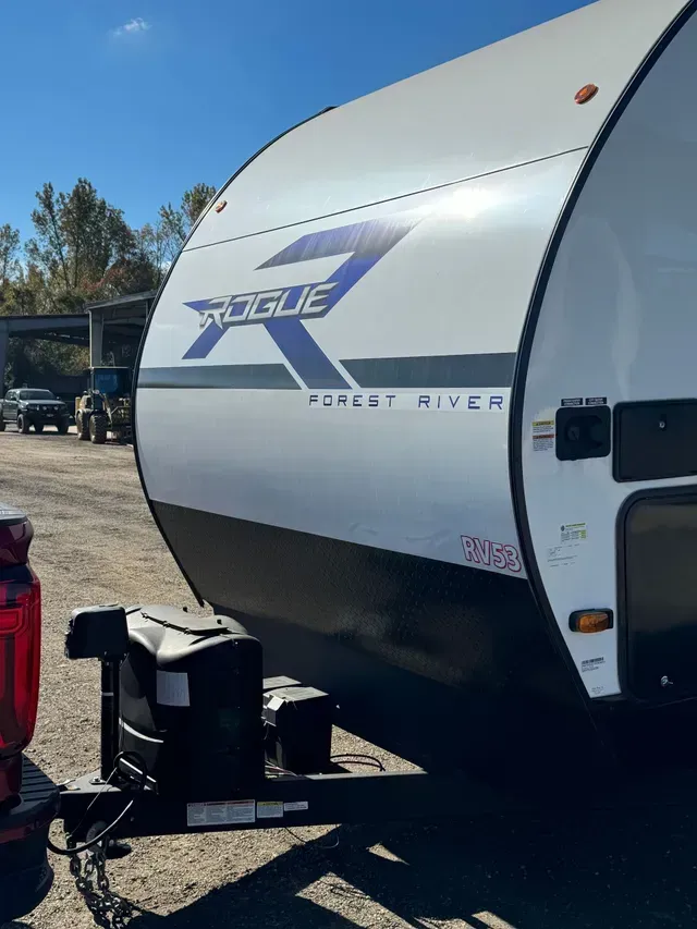 A rogue rv is parked in a parking lot next to a truck.