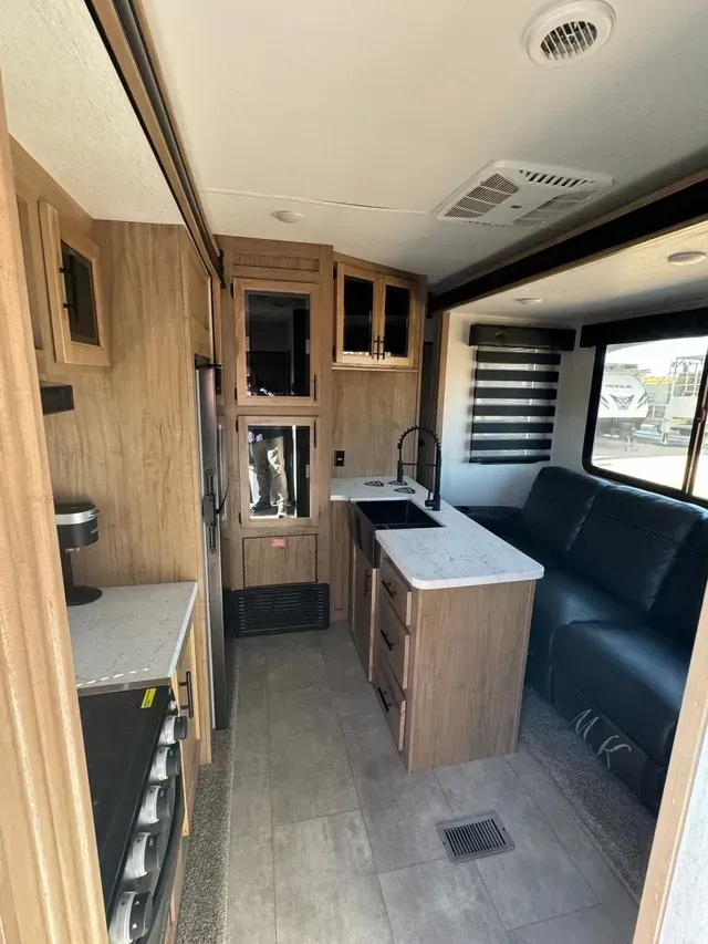 The inside of a rv with a couch and a kitchen.