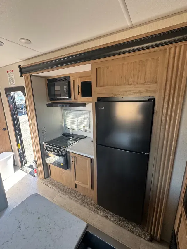 A kitchen with a refrigerator , stove , microwave and sink.
