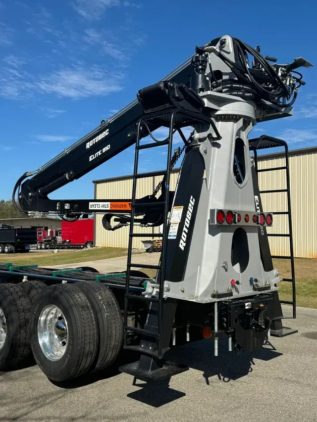 A large crane is attached to the back of a semi truck.
