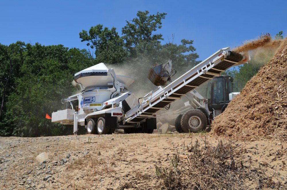 A large pile of dirt is being loaded onto a conveyor belt.