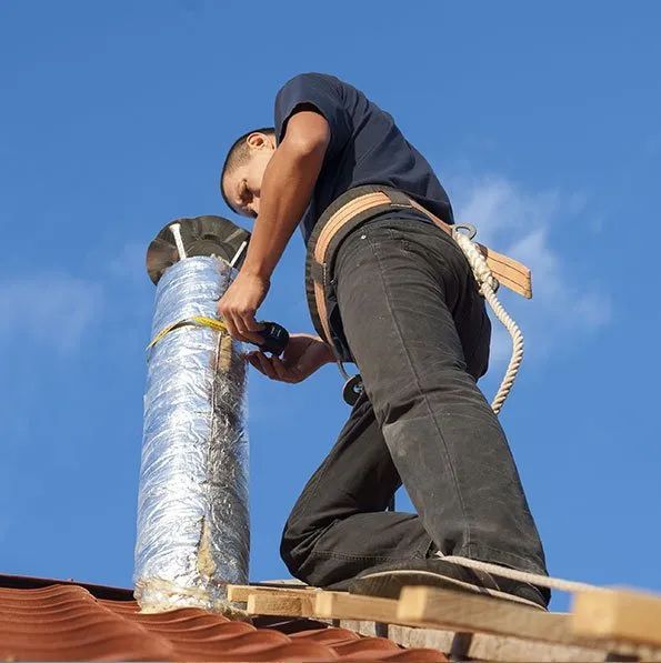 A man is working on a chimney on a roof