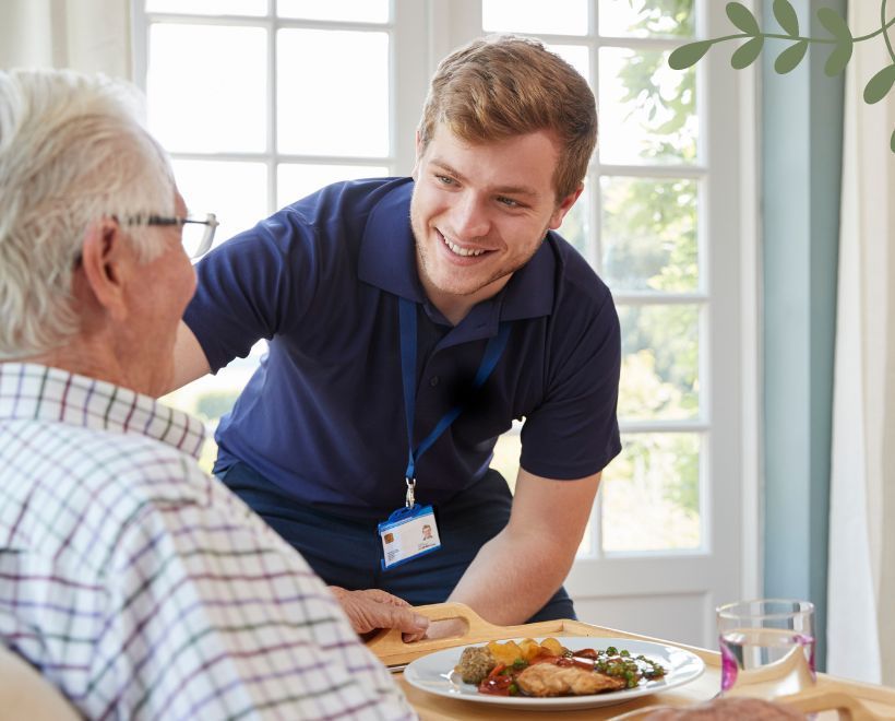 A young man is serving a plate of food to an older man.