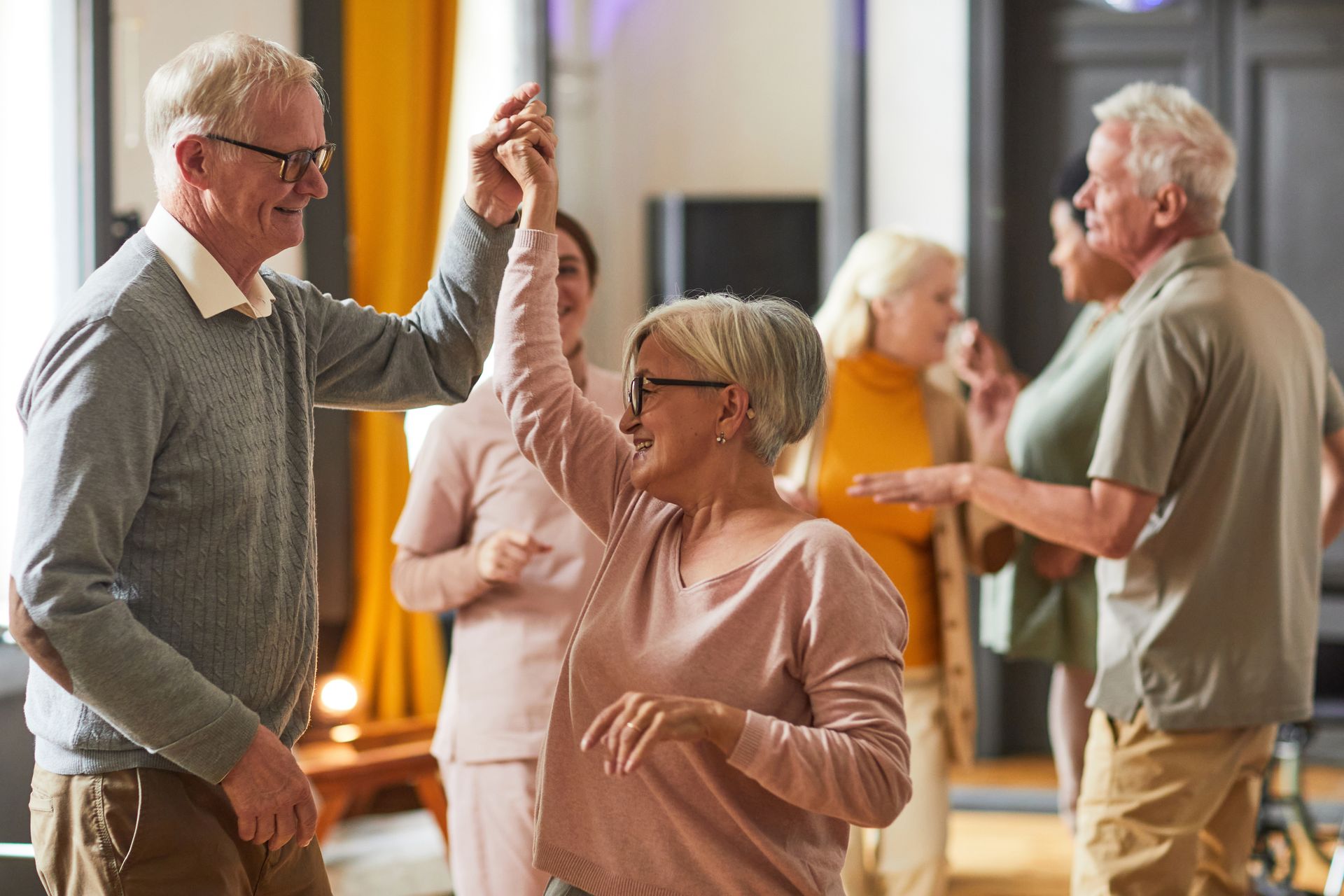 A group of elderly people are dancing together in a living room.