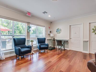 A living room with hardwood floors , two chairs , a table and a window.