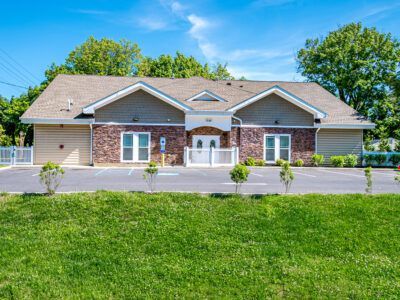 A large house with a lot of windows and doors is sitting on top of a lush green field.