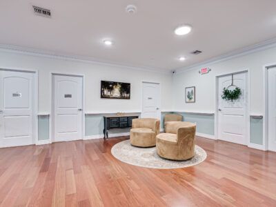 A living room with hardwood floors , two chairs and a table.