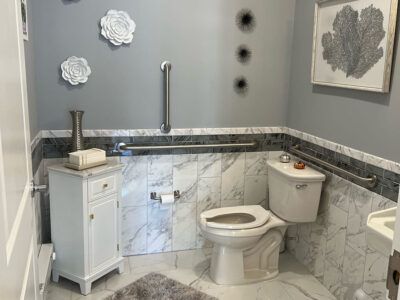 A bathroom with a toilet , sink , and handrails.
