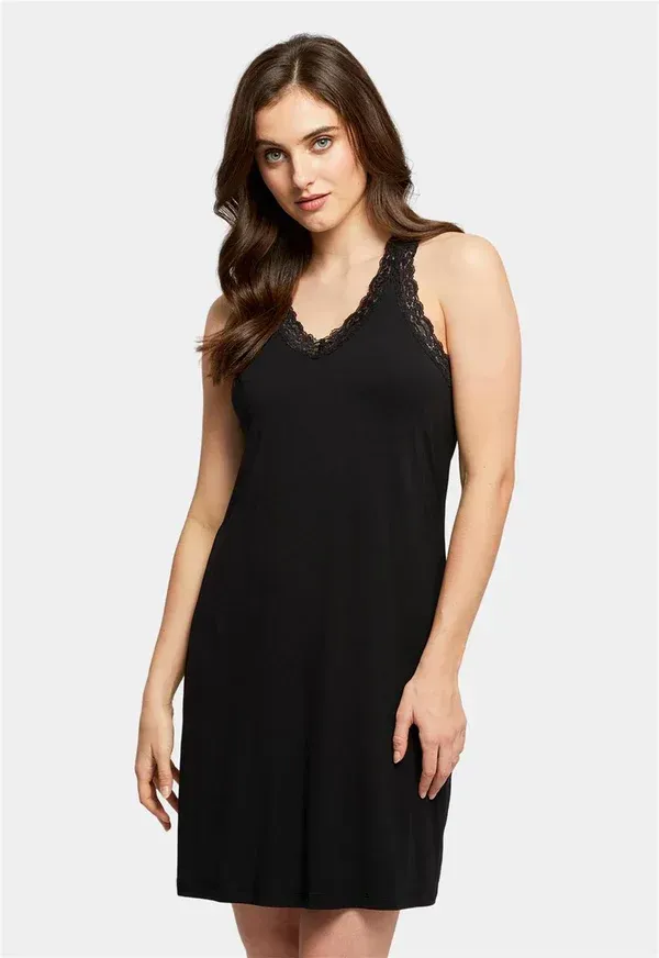 Woman wearing a black nightgown with lace trim, standing in a studio setting.