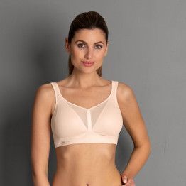 Woman in light peach-colored sports bra, posing.