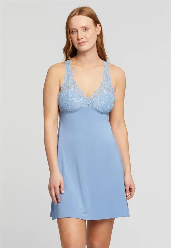 Woman wearing a light blue slip dress with a lace bodice, standing in a studio.