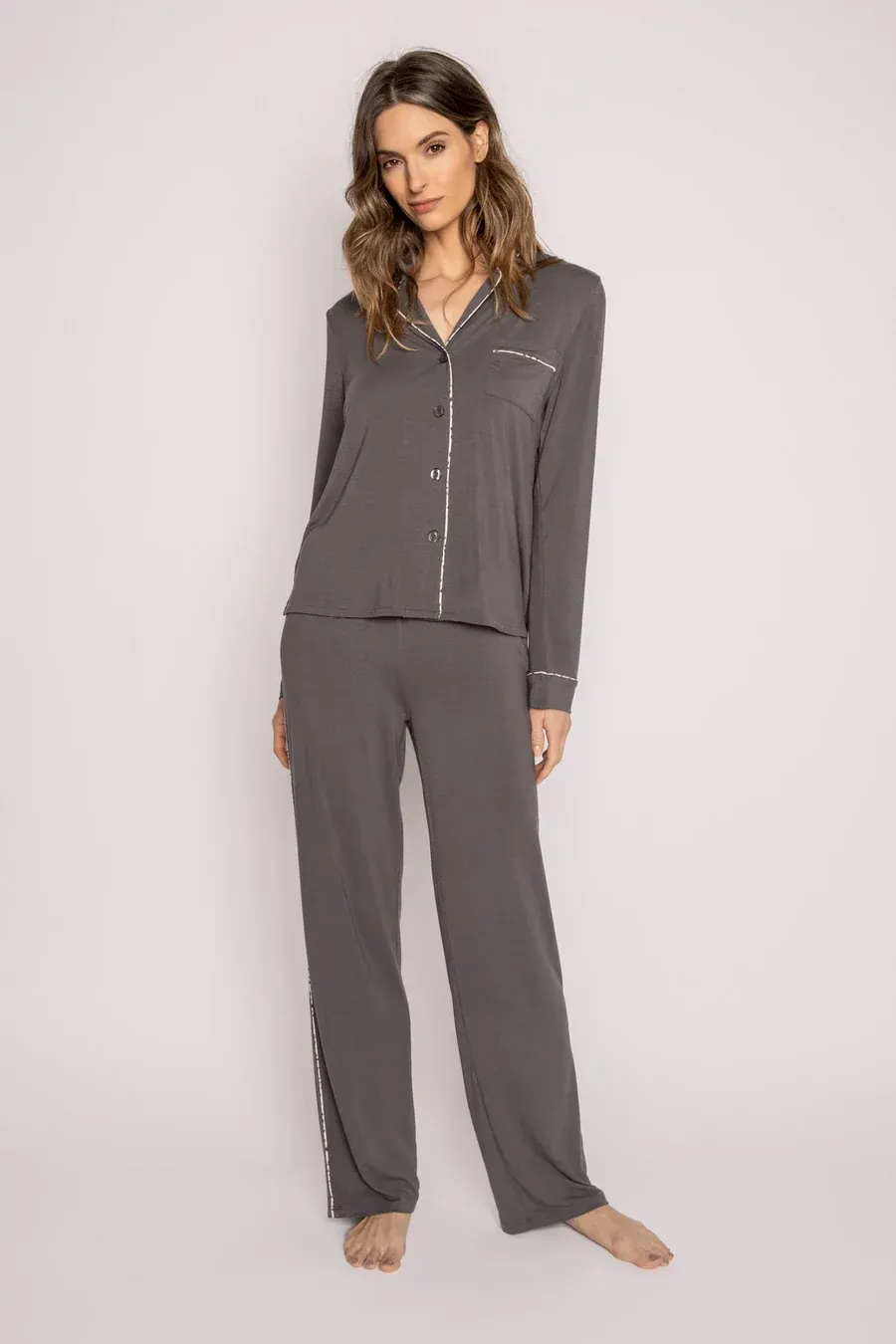 Woman in gray pajama set, standing in a studio with a neutral background.