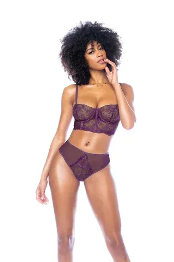 Woman wearing purple lingerie, posing with hand on face.