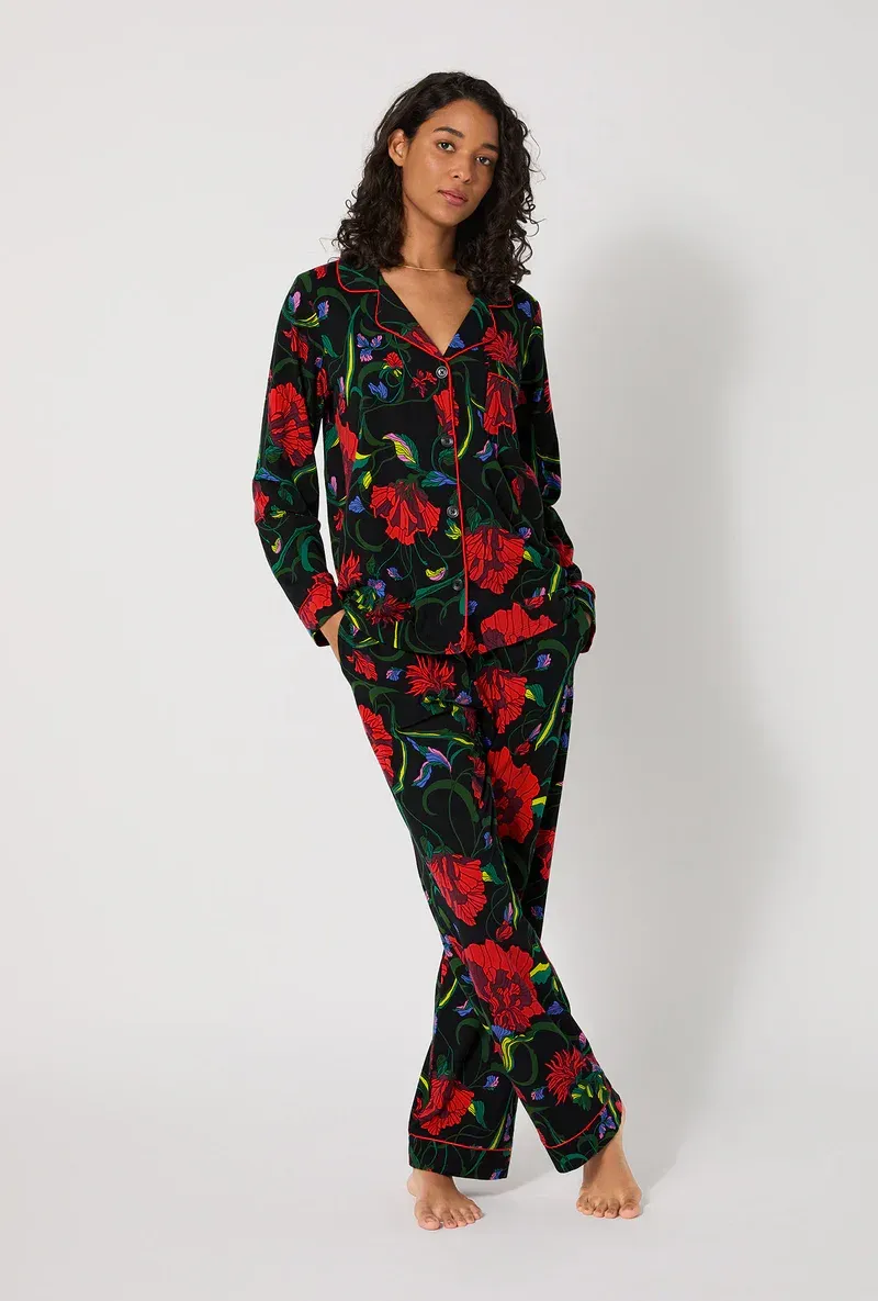Woman in black floral pajamas standing against a white backdrop.