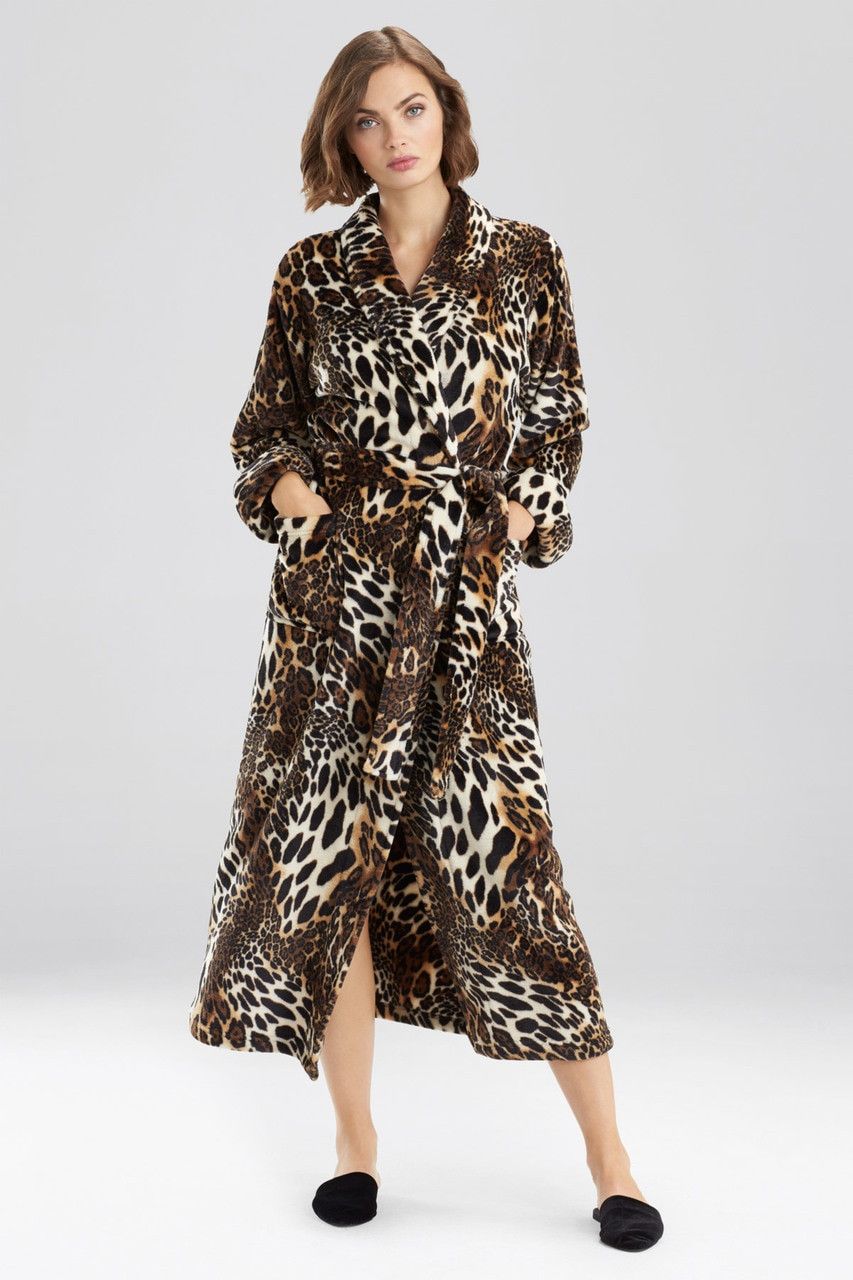 Woman in leopard-print robe with pockets, wearing slippers, standing in a studio with neutral background.